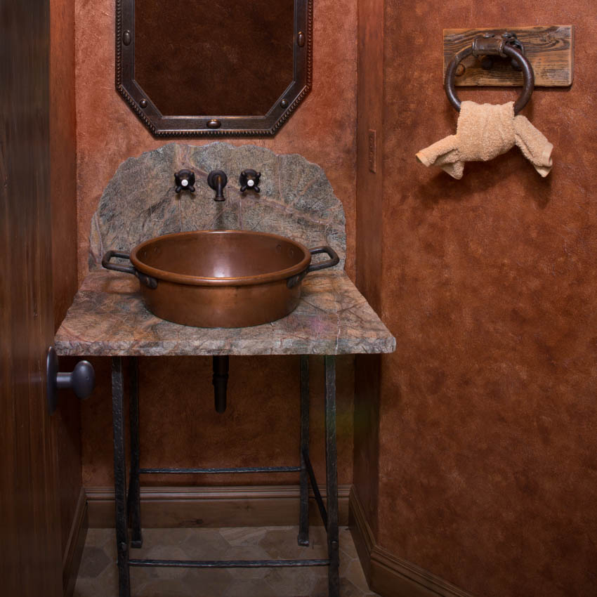 Небольшое пространство ванной комнаты с деревенским медным зеркалом раковины и красной стеной