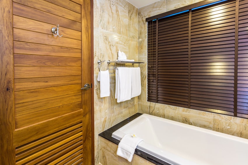 Интерьер ванной комнаты с ванной и деревянными жалюзи
