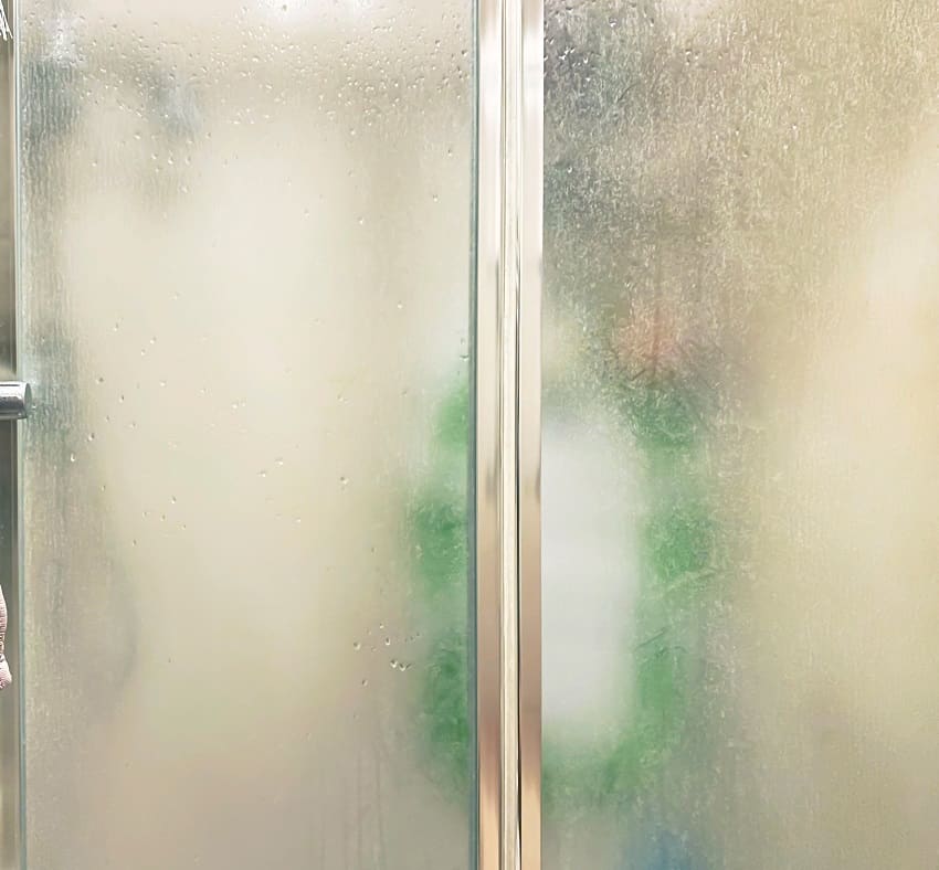 Душевая кабина с дверьми из матового стекла и алюминиевой конструкцией внутри ванной комнаты