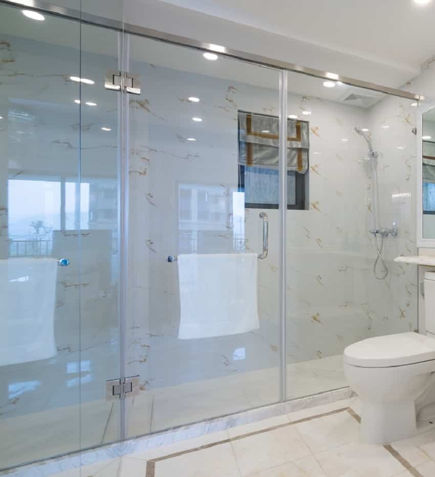 Белая внутренняя ванная комната с прозрачной стеклянной дверью для душа
