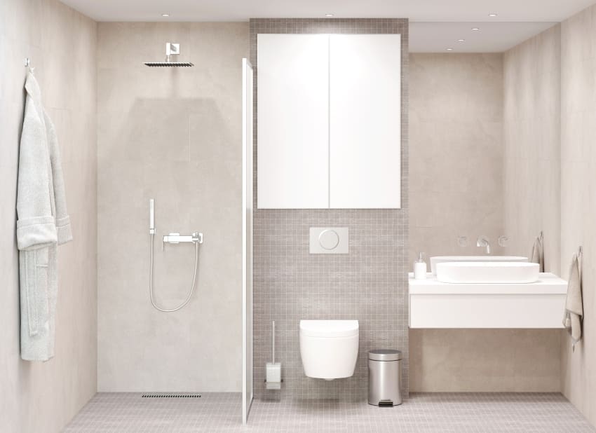 светлая бежевая ванная комната с большим прямоугольным зеркалом над белым умывальником шкафчик над встроенным унитазом душ со стеклянной перегородкой и халат