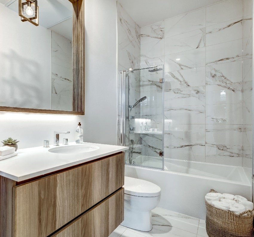 ванная комната с мраморной душевой кабиной, зеркальной корзиной с полотенцами и деревянными шкафчиками