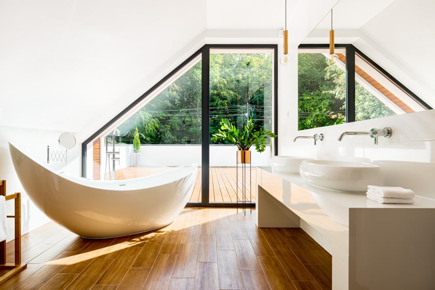 Современная ванная комната с ванной с деревянным настилом и белой раковиной