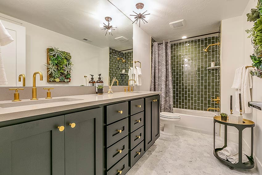 Гостевая ванная комната с зеленой вертикально сложенной глазурованной керамической плиткой и ванной в нише