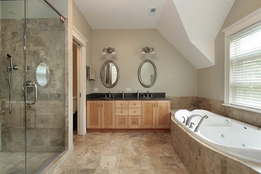 В простом дизайне ванной комнаты используется керамическая плитка из натурального камня в бежевых тонах