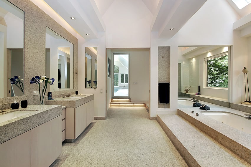 Просторная ванная комната отделана плиткой из натурального известняка с белой краской в ​​полуматовом покрытии и ванной с подъемом вверх.
