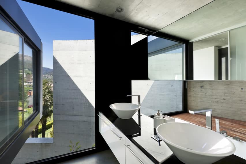 Современная ванная комната с полированным бетоном и окрашенными в черный цвет стенами с раковинами