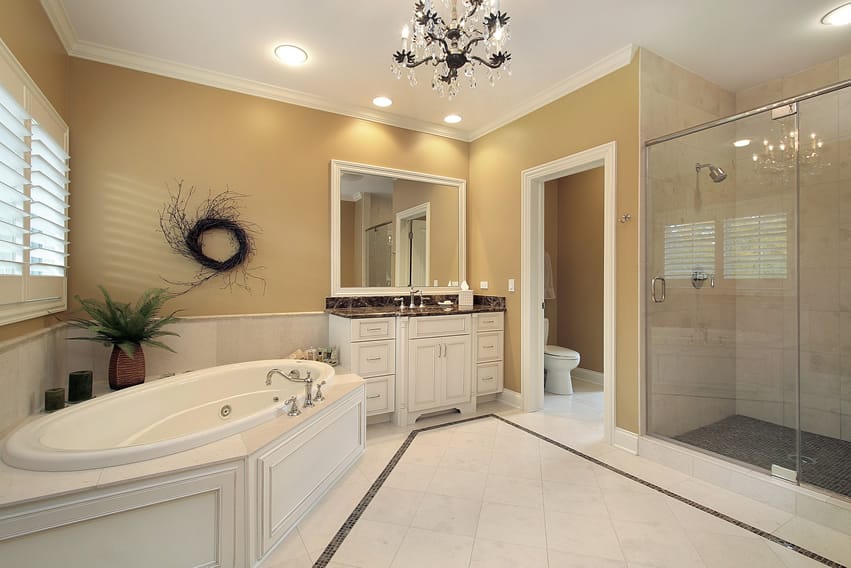 Ванная комната с белой керамической плиткой с темно-серыми каменными мозаичными плитками и красивой стеклянной люстрой