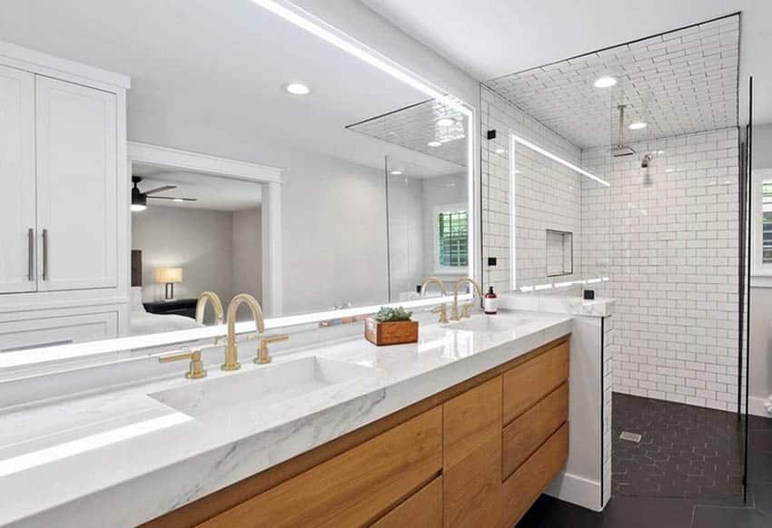 Ванная комната с двойной раковиной, белыми шкафчиками с золотой отделкой и коричневой раковиной с мраморной столешницей.