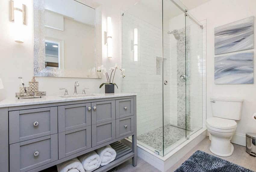 Ванная комната с длинной белой плиткой метро, ​​душевой кабиной, мозаичной плиткой, серым туалетным столиком и полами из керамогранита