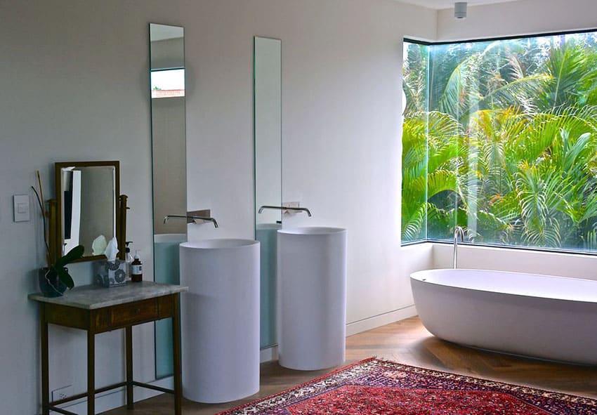 Красивая главная ванная комната с акриловой ванной и современными раковинами на пьедестале