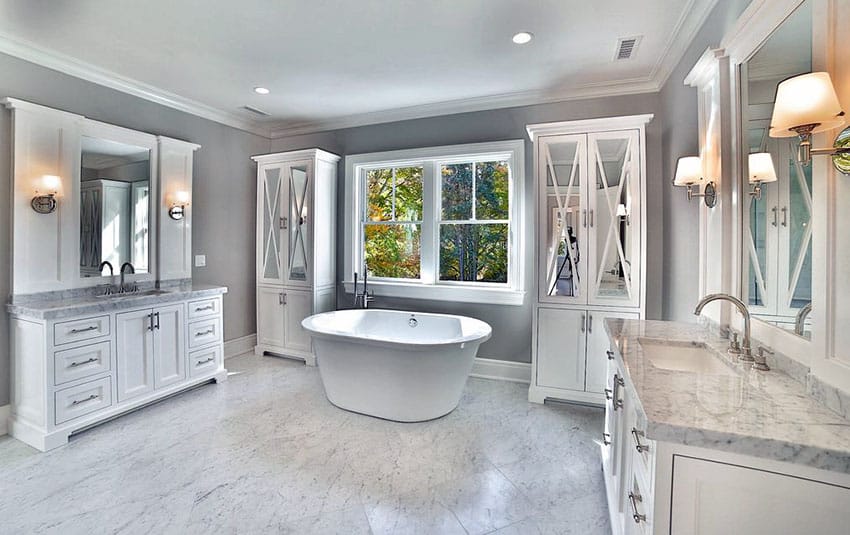 Красивая ванная комната с отдельно стоящей ванной, видом на улицу, полом и столешницей из белого мрамора.