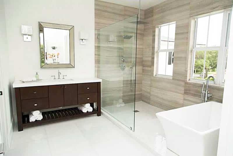 Современная ванная комната с потолочным тропическим душем и отдельно стоящей ванной