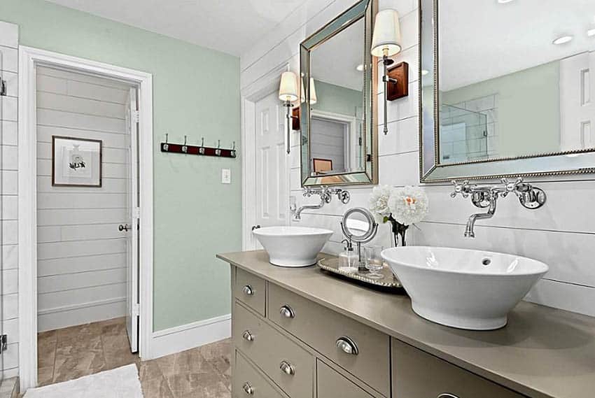 Небольшая ванная комната с зеленой краской, белой корабельной обшивкой и двойными раковинами