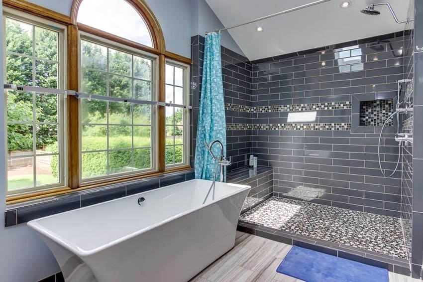 Современная главная ванная комната с душем из стеклянной плитки и скамьей с отдельно стоящей ванной.