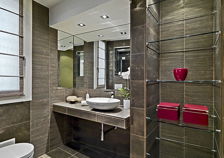 Небольшая ванная комната с темно-коричневой плиткой и стеклянными полками