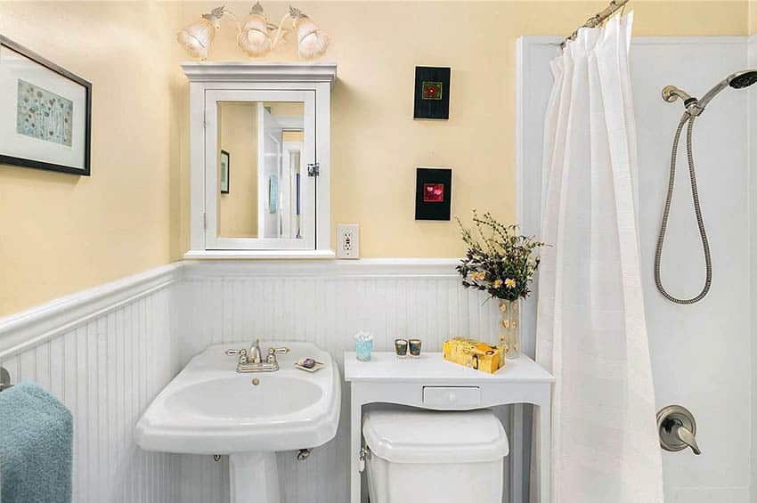 Гостевая ванная комната с белыми панелями и окрашенными в желтый цвет стенами с раковиной на пьедестале
