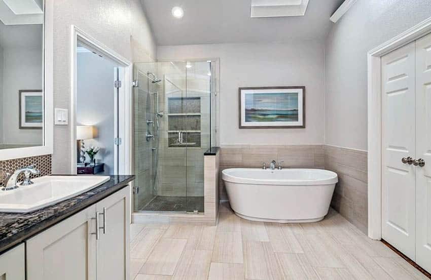 Ванная комната с отдельно стоящей ванной, облицованной плиткой, и полом из керамогранита