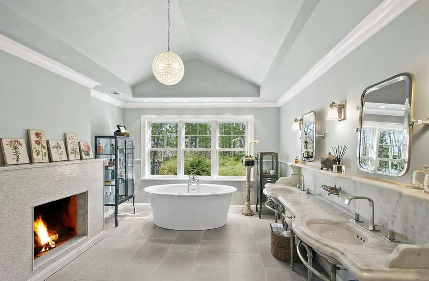 Основная ванная комната с полом из керамогранита, отдельно стоящей ванной, камином и люстрой в форме шара.