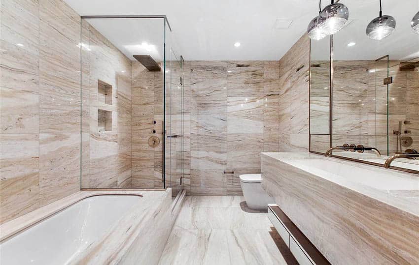 Современная ванная комната с плиткой из известняка, стеклянной душевой кабиной и плавающей раковиной.