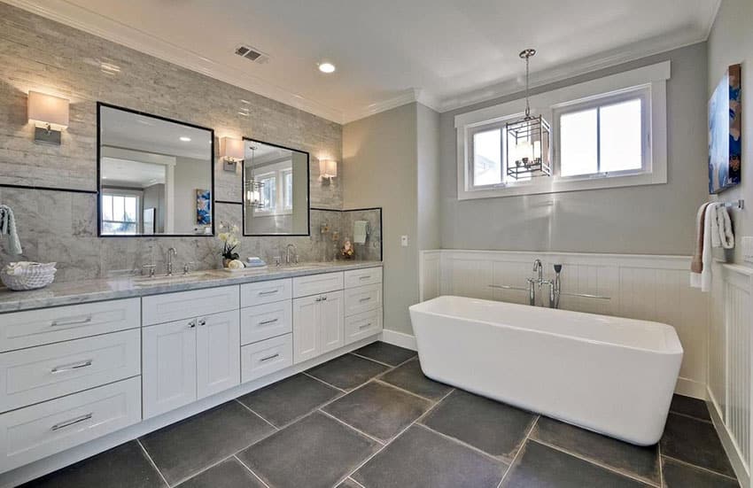 Современная главная ванная комната с напольной плиткой из черного сланца, ванной на пьедестале и белым туалетным столиком.
