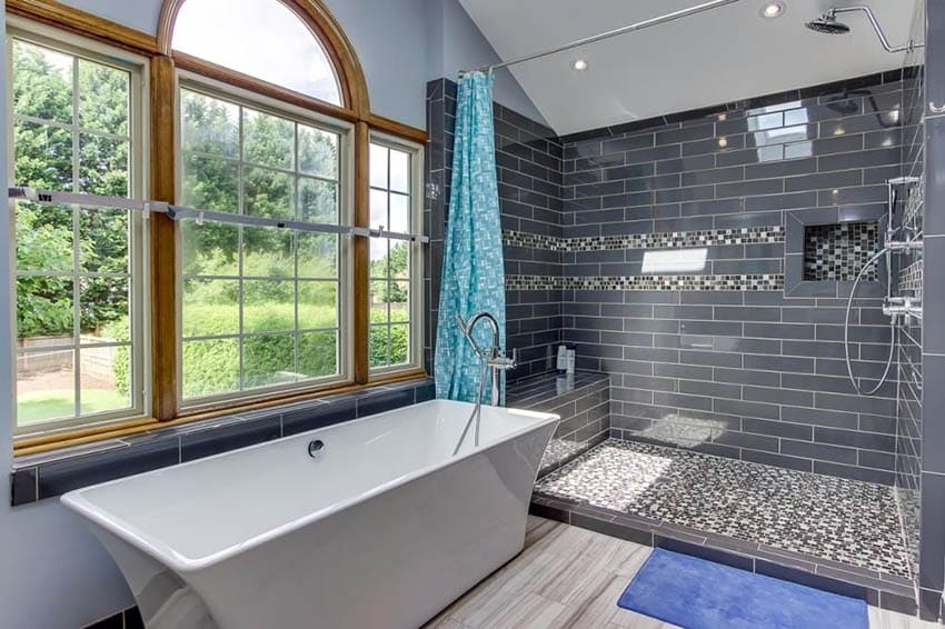 Современная главная ванная комната с душевыми стенами, выложенными стеклянной плиткой, и отдельно стоящей ванной.