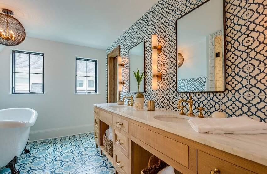 Bathroom with brass hardware blue and white patterned tile floor and wall stone countertops lighting fixtures and free free standing tub