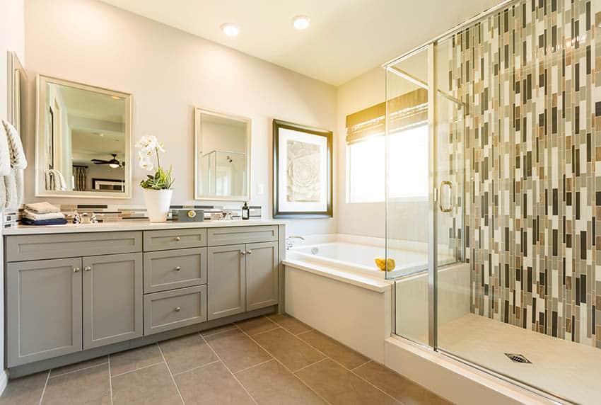 Ванная комната со светло-желтой краской, ванной в нише и душем, выложенным мозаичной плиткой.