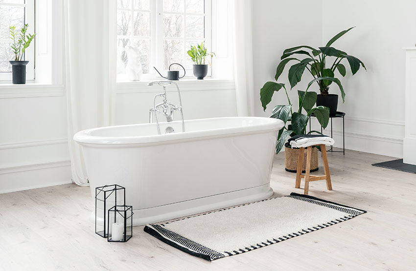 Светлая ванная комната со скандинавским дизайном интерьера с ванной и ковриком ss
