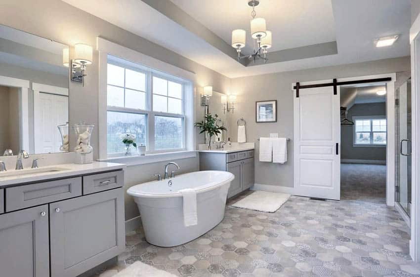 Великолепная современная ванная комната с серой раковиной для него и для нее и отдельно стоящей ванной.